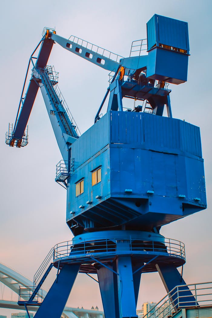 Large blue dockyard crane towering against a pastel sky. Industrial and maritime theme.