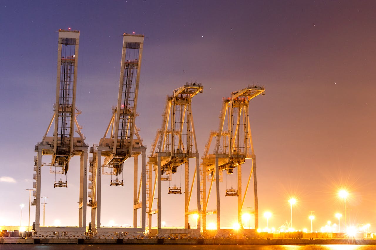 A stunning view of illuminated harbor cranes against a night sky.